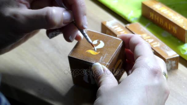 mano di una donna dipingere un numero su un cubo di legno con un pennello punta rotonda
 - Filmati, video