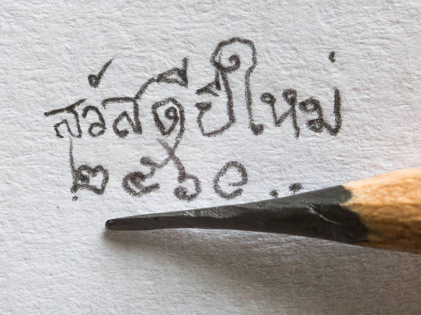 Zbliżenie dłoni pisania szczęśliwego nowego roku 2017 w thai słowo, Sawaddee mai siusiu, na papierze ołówkiem - Zdjęcie, obraz