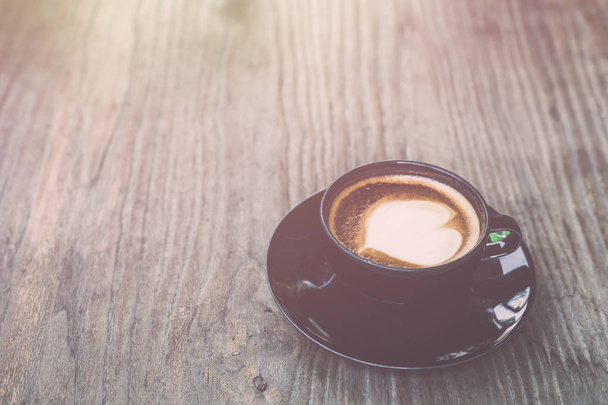 Hot latte coffee in black cup on grey wooden table background. V - Fotó, kép