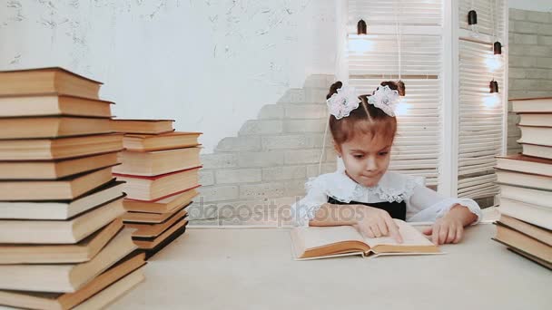 Schoolmeisje zitten aan een tafel en lezen van een boek. - Video