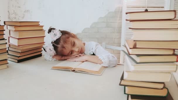 Klein meisje in schooluniform, viel in slaap tijdens het lezen van een boek. - Video