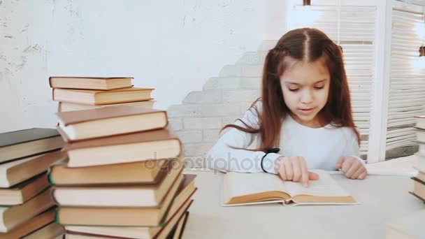Κορίτσι με όμορφα μαύρα μαλλιά κάθεται σε ένα τραπέζι και διαβάζει λογοτεχνία. - Πλάνα, βίντεο
