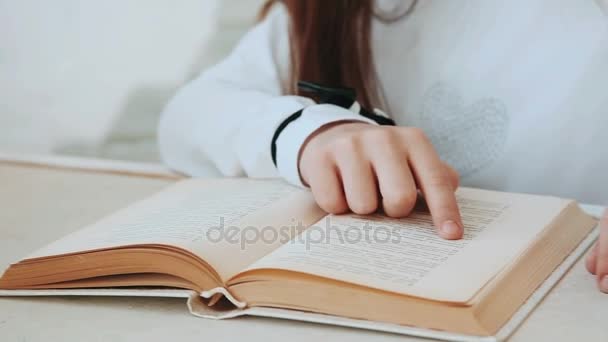 Το χέρι της ένα κοριτσάκι οδηγεί από την σελίδα του βιβλίου. - Πλάνα, βίντεο