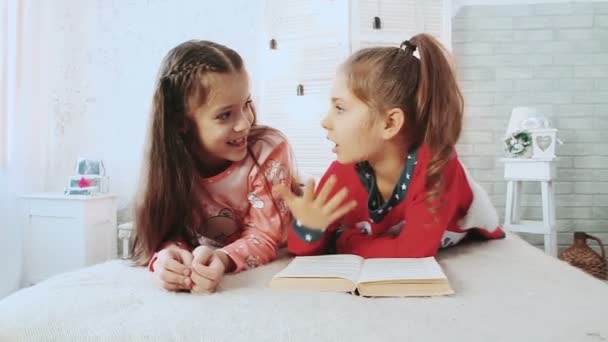 Kaksi pientä ystävää pyjamassa ja he lukevat kirjaa. He puhuvat ja keskustelevat kirjasta
. - Materiaali, video