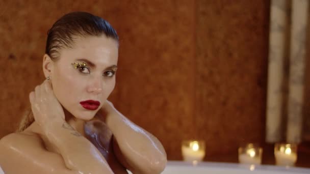 charming woman with bright makeup looking at camera taking bath - Materiał filmowy, wideo