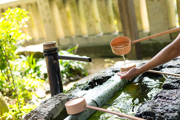 Donna che si lava la mano prima di andare al tempio giapponese
 - Foto, immagini