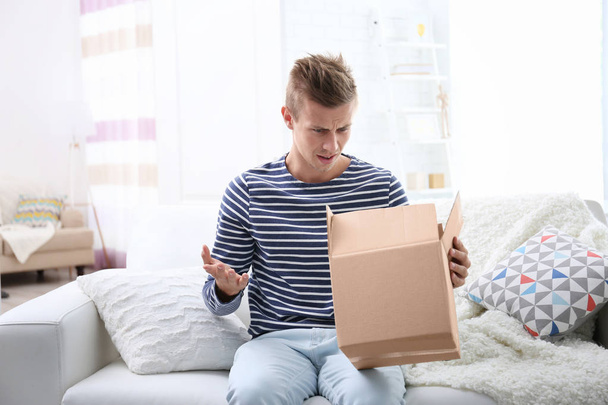 Young man unpacking parcel - Foto, afbeelding