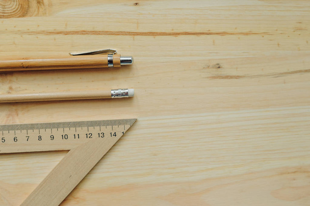 Деревянный карандаш, ручка, треугольник на столе при дневном свете
 - Фото, изображение