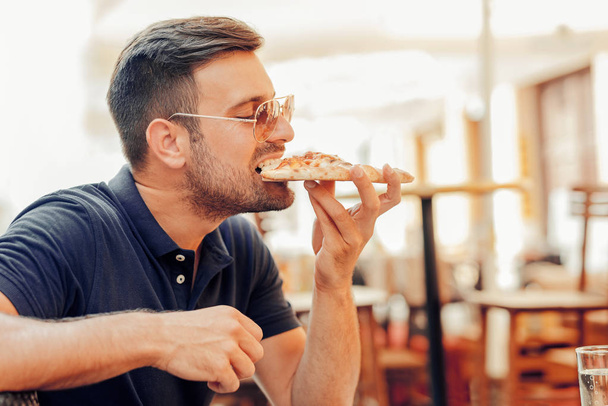 Homme mangeant de la pizza
 - Photo, image