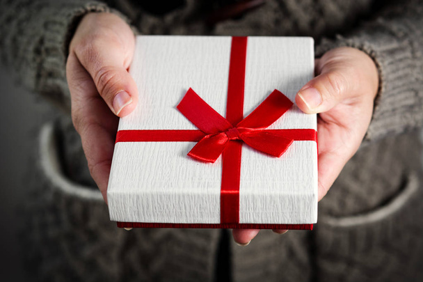 Bir hediye kutu kırmızı kurdele ile tutan eller. Yakın çekim. - Fotoğraf, Görsel