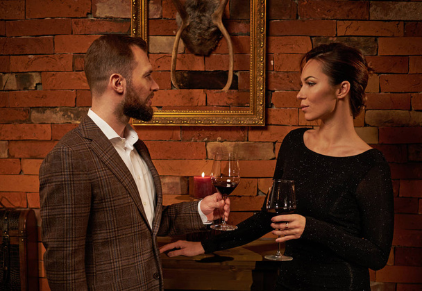 Dobrze ubrany para z kieliszek czerwonego wina w przytulne wnętrze domu - Zdjęcie, obraz