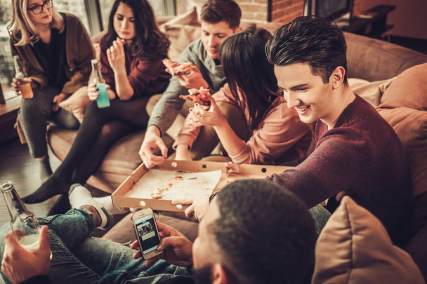 Skupina více etnických mladí přátelé, jíst pizzu v domácí interiér - Fotografie, Obrázek