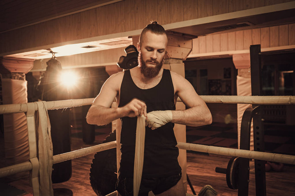 Combatiente preparándose para el entrenamiento, envolviendo las manos con envolturas de boxeo
 - Foto, Imagen