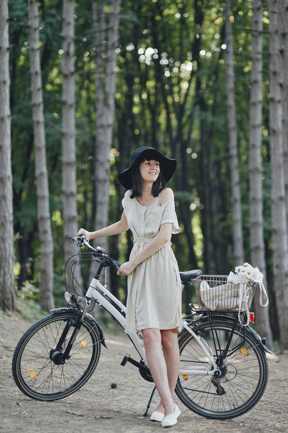 Young woman against nature background with bike - Foto, afbeelding