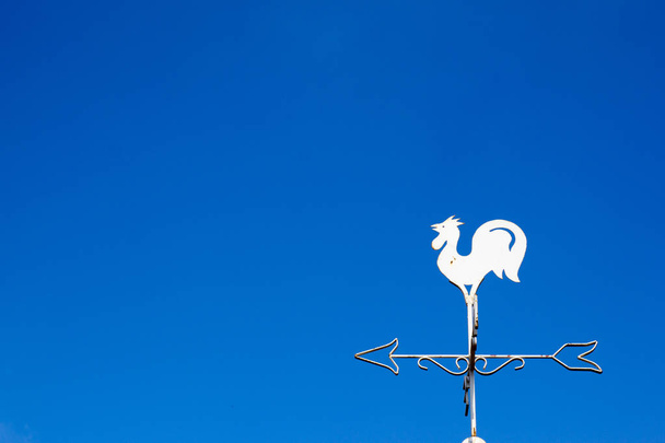 weiße Hahn Wetterfahne zeigt die Windrichtung auf blauem Himmel Hintergrund - Foto, Bild