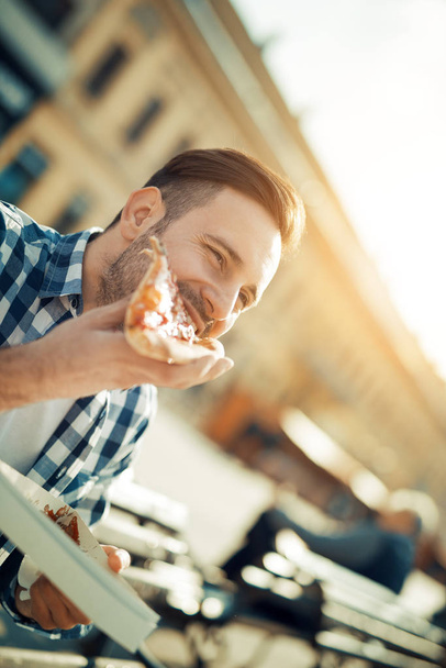 schöner junger Mann isst ein Stück Pizza  - Foto, Bild