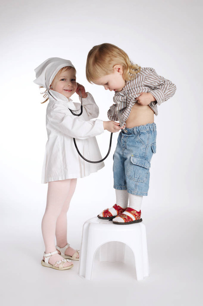 boy and girl playing doctor on white - Foto, immagini