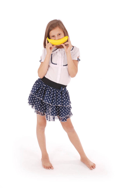 Молодая девушка держит банан у рта, имитируя улыбку
 - Фото, изображение