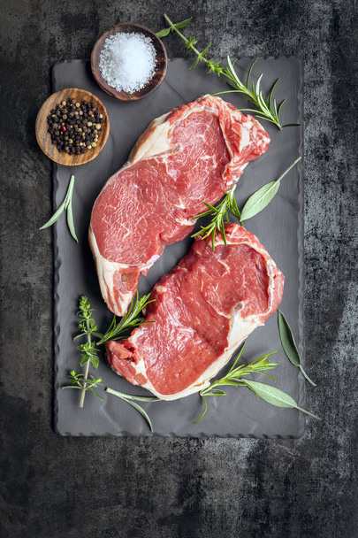 Syrové hovězí steaky na břidlicové pohled shora s bylinkami a kořením - Fotografie, Obrázek