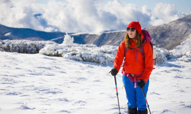 Meisje met rugzak lopen op sneeuw in de bergen. - Foto, afbeelding