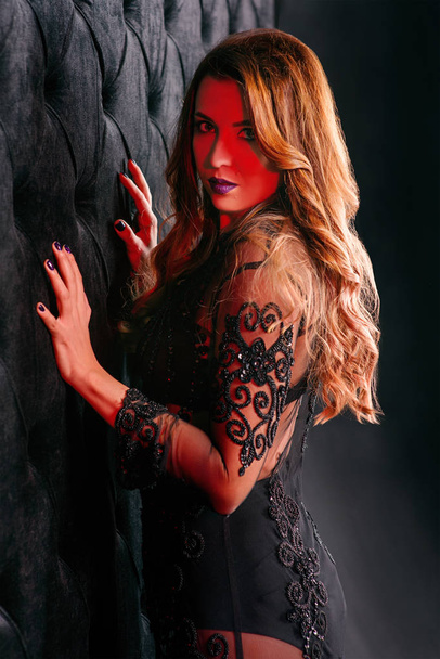 Νέοι όμορφη ελκυστική και ζεστό μακριά μαλλιά γυναίκα στο μαύρο εσώρουχο κοντά σε μαύρο βελούδο τοίχο σε φωτογραφία στούντιο - Φωτογραφία, εικόνα