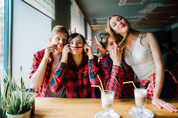 Group of young friends hanging out at a coffee shop. Young men and women meeting in a cafe having fun and drinking coffee. Lifestyle, friendship and urban life concepts. - Photo, Image