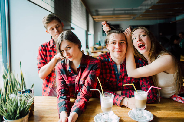 Group of young friends hanging out at a coffee shop. Young men and women meeting in a cafe having fun and drinking coffee. Lifestyle, friendship and urban life concepts. - Foto, Imagen