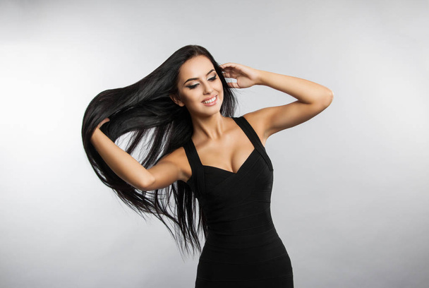 Beautiful girl model touches her hair. A brunette woman in a black dress - Foto, Imagem
