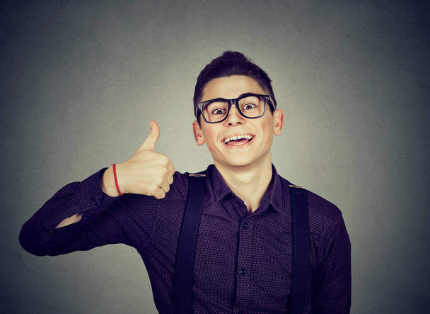 Successful teenager. Nerdy man giving thumbs up hand gesture sign  - 写真・画像