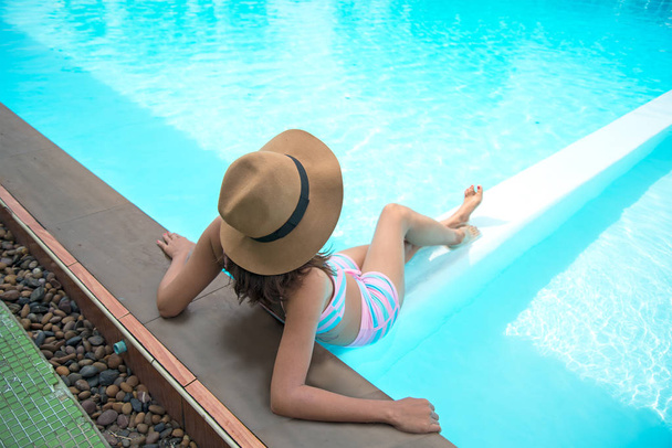 junge Frau mit dickem Hut entspannt sich am Pool - Foto, Bild