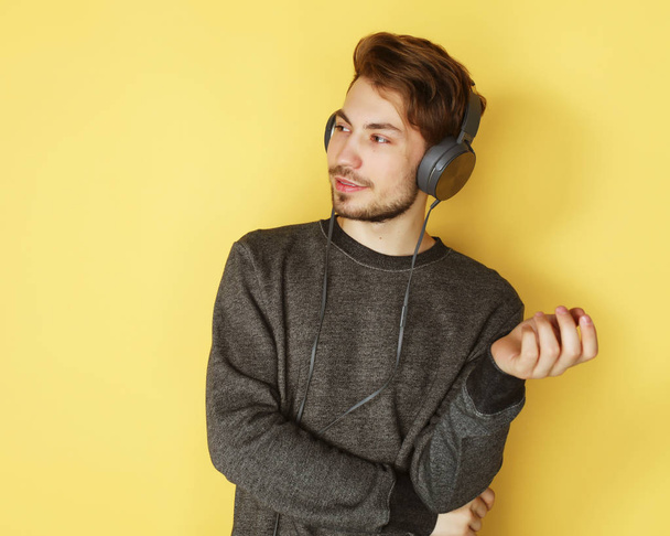 Handsome Man lictening to music over yellow background - Foto, afbeelding