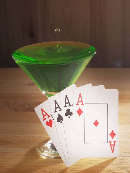Glass with a cocktail and playing cards . wooden background - Foto, afbeelding