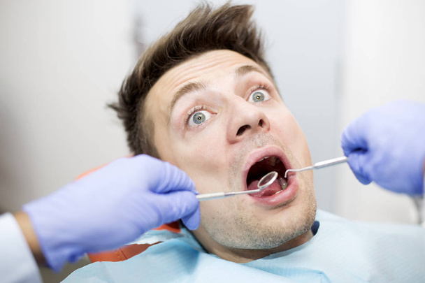verängstigter junger Mann in Zahnarztpraxis - Foto, Bild