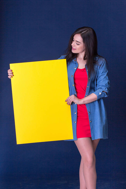 Happy woman holding a yellow blank sheet of paper - Fotó, kép