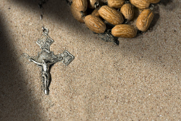 Zilveren Crucifix met rozenkrans kralen op zand - Foto, afbeelding