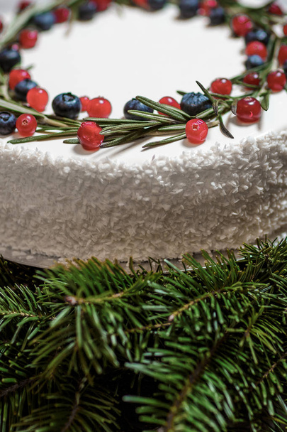 Christmas cake with berries on the background of fir branches - Foto, afbeelding