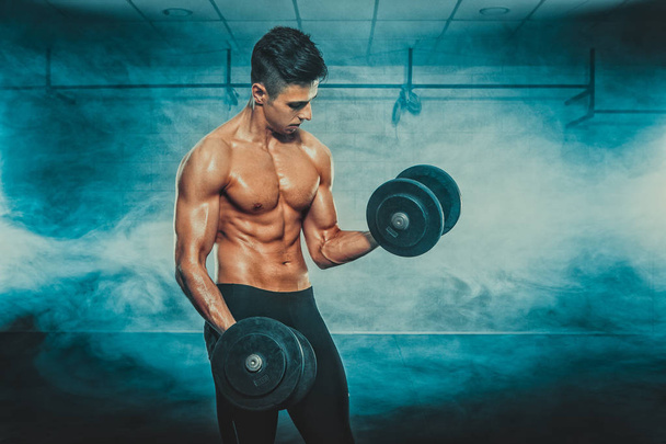 Young man standing with dumbbells - Foto, imagen