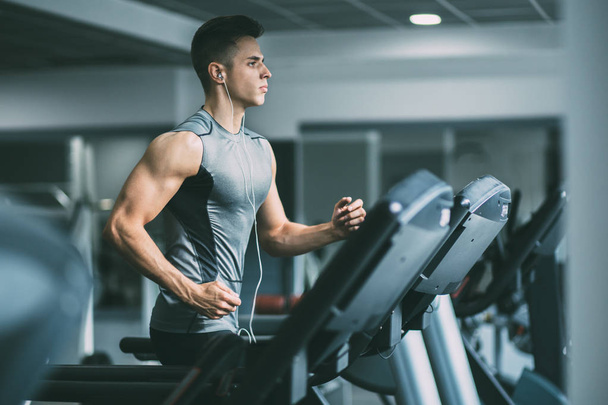 Man in sportswear running on treadmill  - Foto, Bild