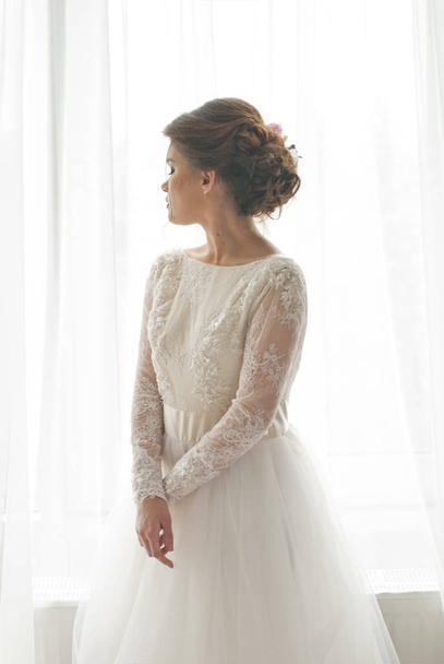 Πορτρέτο του όμορφη νεαρή νύφη κατά ένα παράθυρο στο εσωτερικό - Φωτογραφία, εικόνα