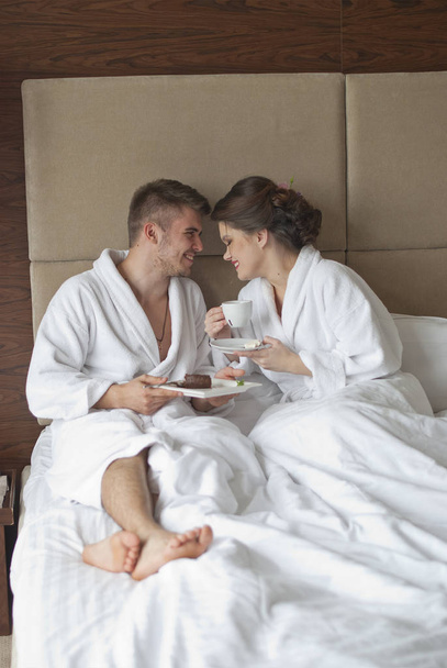 ベッドで朝食を持っている美しい笑顔若いカップル - 写真・画像