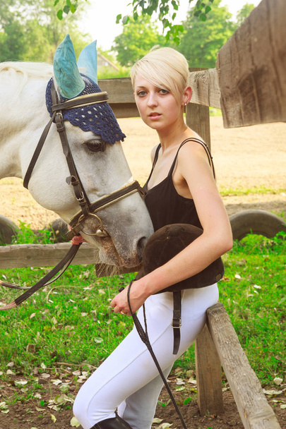 νεαρή γυναίκα δίπλα σε ένα άσπρο άλογο - Φωτογραφία, εικόνα