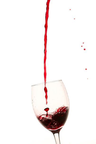 Glas gefüllt mit einem Rotwein auf weißem Hintergrund - Foto, Bild
