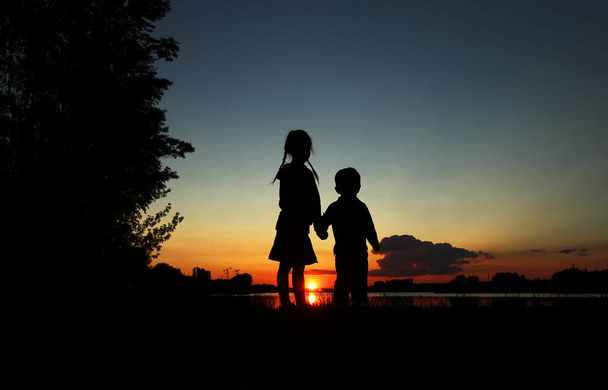 a két gyerek kézenfogva sziluettek - Fotó, kép