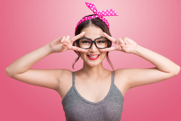 Fashion portrait of asian girl with sunglasses standing on pink  - Photo, Image