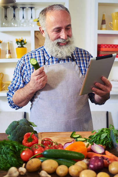 Hombre moderno en busca de una receta con la ayuda de la tableta de pie
 - Foto, Imagen