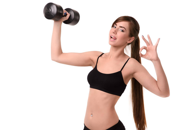 young smiling girl shows playful language and holds dumbbell,  gesture okay hand on white background fitness - Foto, Imagem