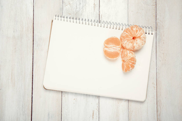 Slices of tangerine (mandarin) with blank notebook - Foto, imagen