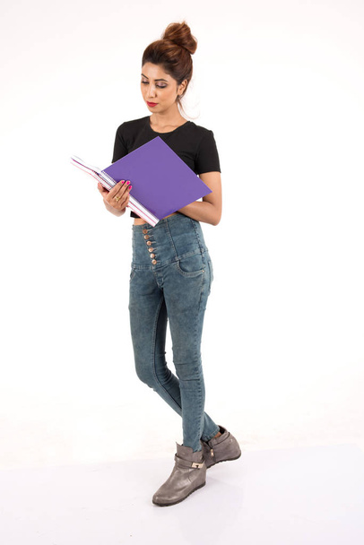 Attractive young female student carrying books on white background - 写真・画像