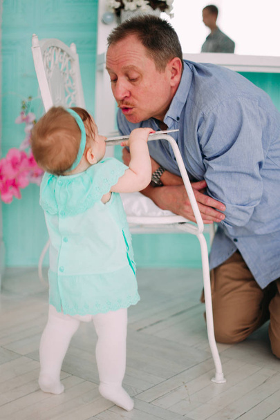Retrato de un abuelo vistiendo camisa azul con su pequeña nieta bonita abrazándolo y escuchando atentamente, filmado en el estudio
 - Foto, Imagen