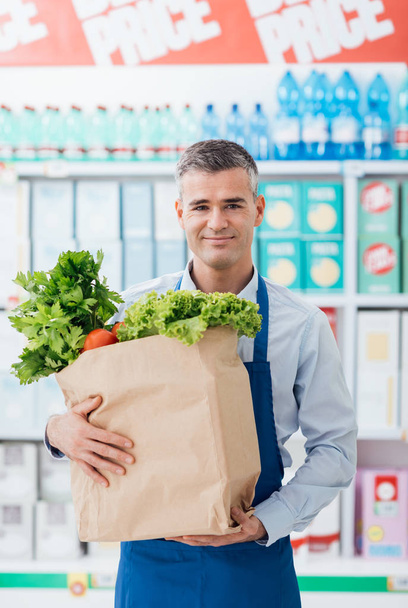 Shop assistant holding grocery bag - Φωτογραφία, εικόνα